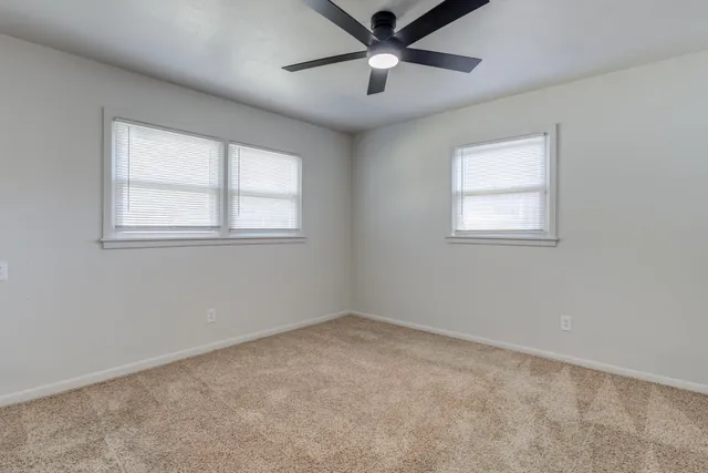 an empty room with a window and a fan