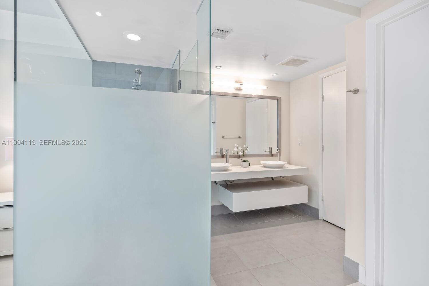 92 Southwest 3rd Street, Unit 310 Miami, FL 33130 - Photo 18 of 40 a bathroom with a double vanity sink and mirror