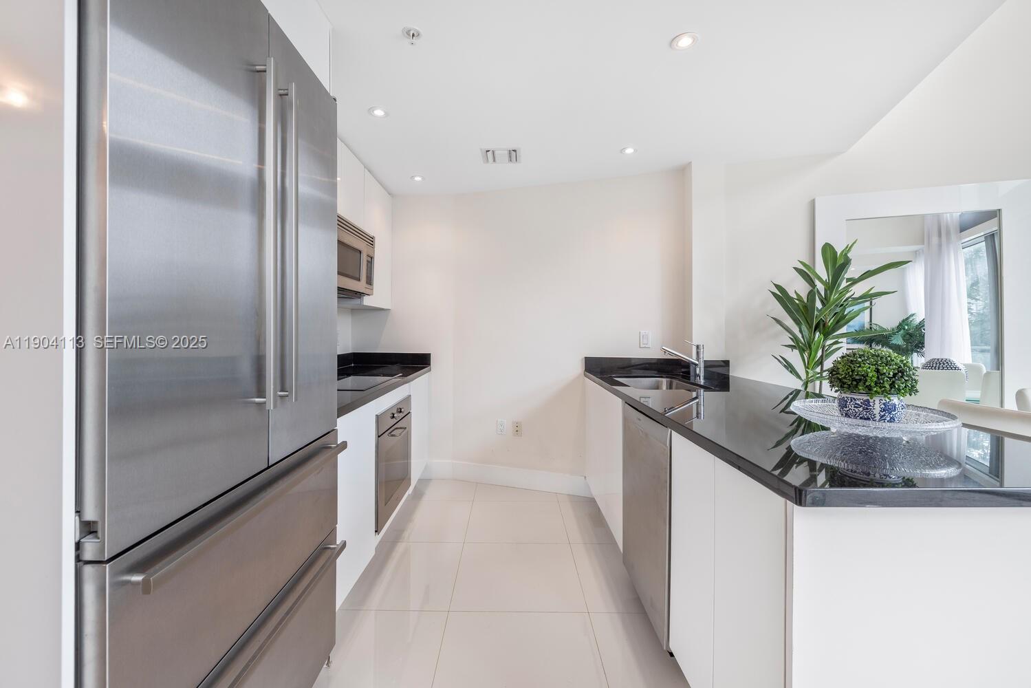 92 Southwest 3rd Street, Unit 310 Miami, FL 33130 - Photo 6 of 40 a kitchen with a potted plant on a counter top space and stainless steel appliances