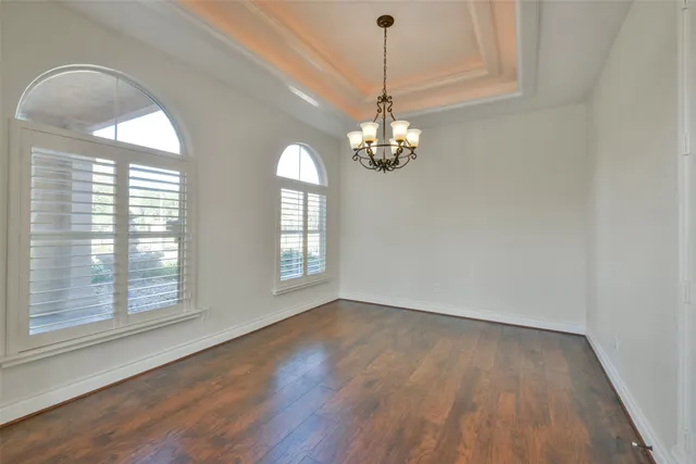 an empty room with wooden floor ceiling fan and windows