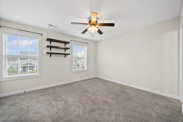 an empty room with windows and fan