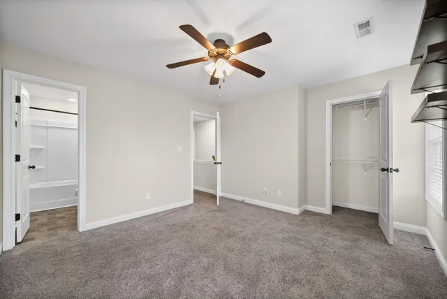 an empty room with closet and ceiling fan