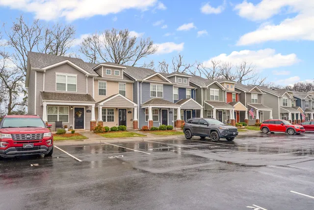 a front view of a building with lot of cars and trees
