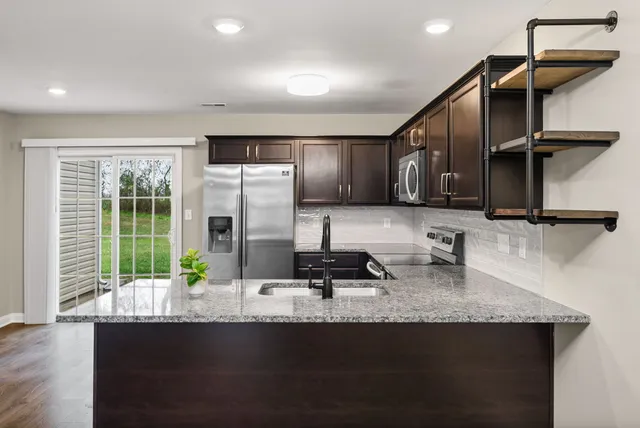 a kitchen with stainless steel appliances granite countertop a sink a stove and a wooden cabinets