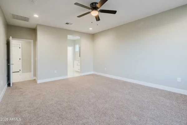 an empty room with chandelier fan and windows