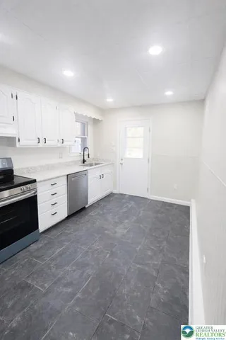 a large white kitchen with granite countertop white cabinets and stainless steel appliances