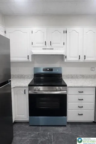 a large white kitchen with granite countertop white cabinets and stainless steel appliances