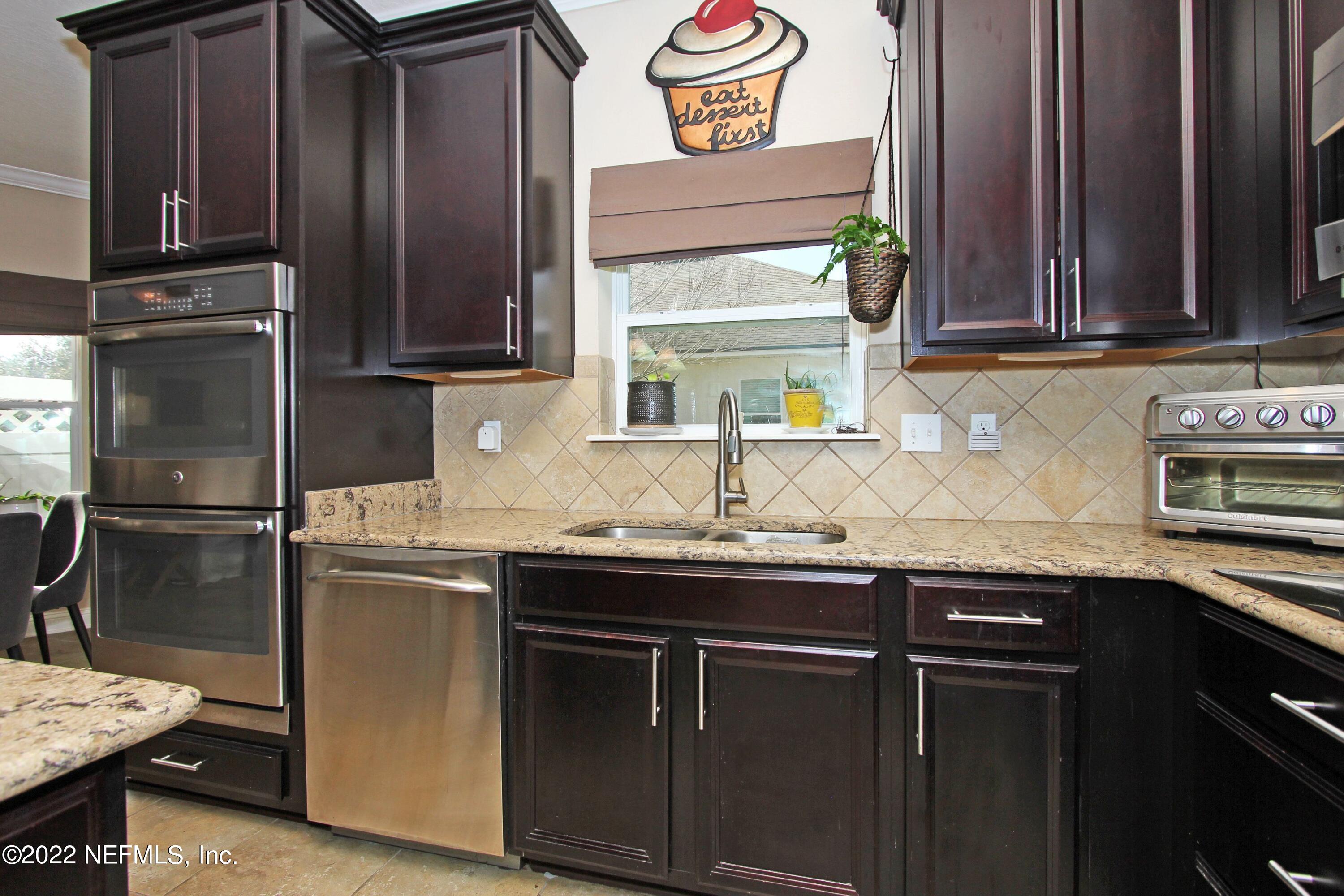 404 Paisley Place St. Johns, FL 32259 - Photo 14 of 42 a kitchen with granite countertop stainless steel appliances a sink stove and refrigerator
