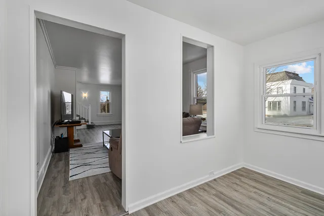 a view of a hallway with wooden floor and a living room