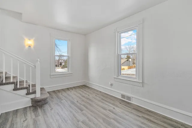 an empty room with wooden floor and windows