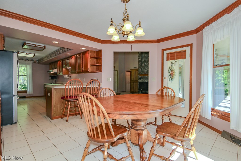 6475 Taylor Road Painesville, OH 44077 - Photo 8 of 23 Dining area featuring tile flooring, a chandelier, wood trim, and a patio door