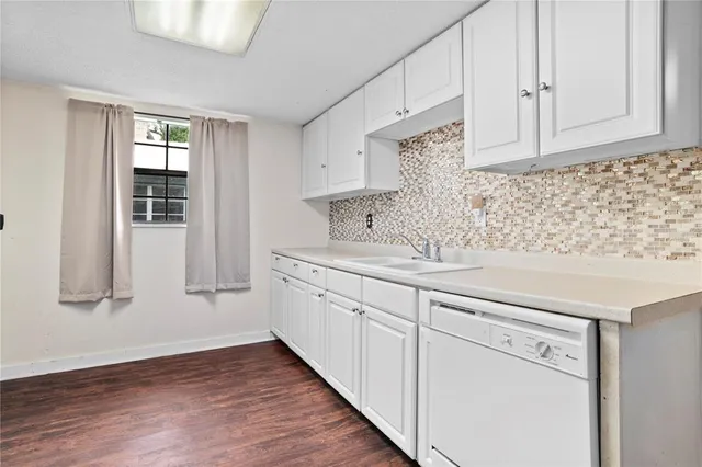 a kitchen with granite countertop white cabinets and a wooden floor