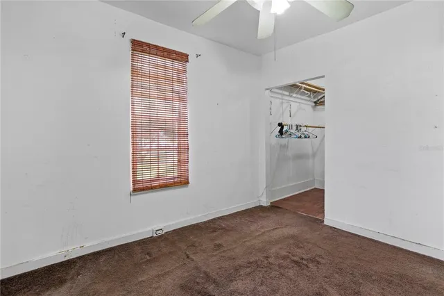 an empty room with a ceiling fan and a window