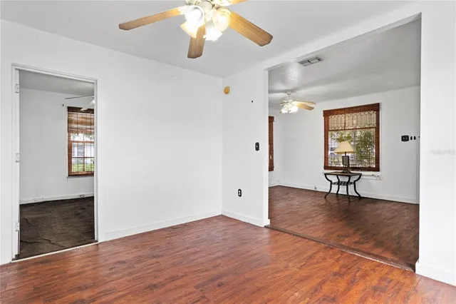an empty room with wooden floor and windows