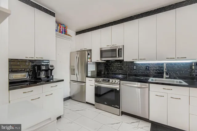 a kitchen with white cabinets and stainless steel appliances