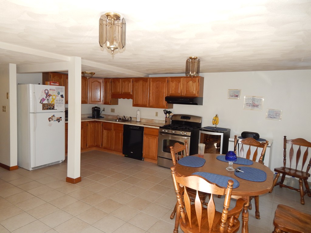 274 Athens Street Boston, MA 02127 - Photo 8 of 23 a kitchen with stainless steel appliances granite countertop a stove top oven a refrigerator a dining table and chairs with wooden floor