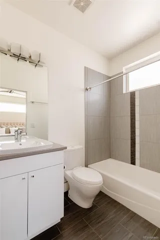 a bathroom with a granite countertop sink toilet a large mirror a bathtub and shower