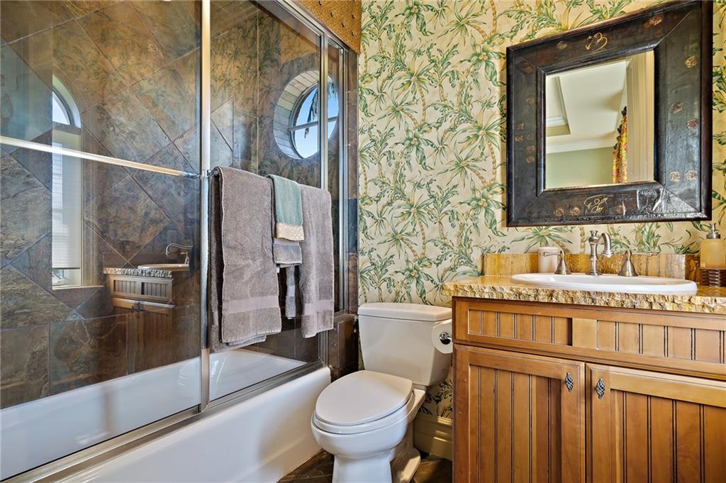 1025 Northeast Doubloon Drive Stuart, FL 34996 - Photo 63 of 69 a bathroom with a granite countertop toilet a sink and a mirror