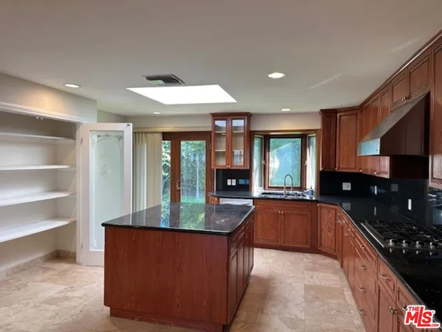 a large kitchen with granite countertop a large counter top and stainless steel appliances