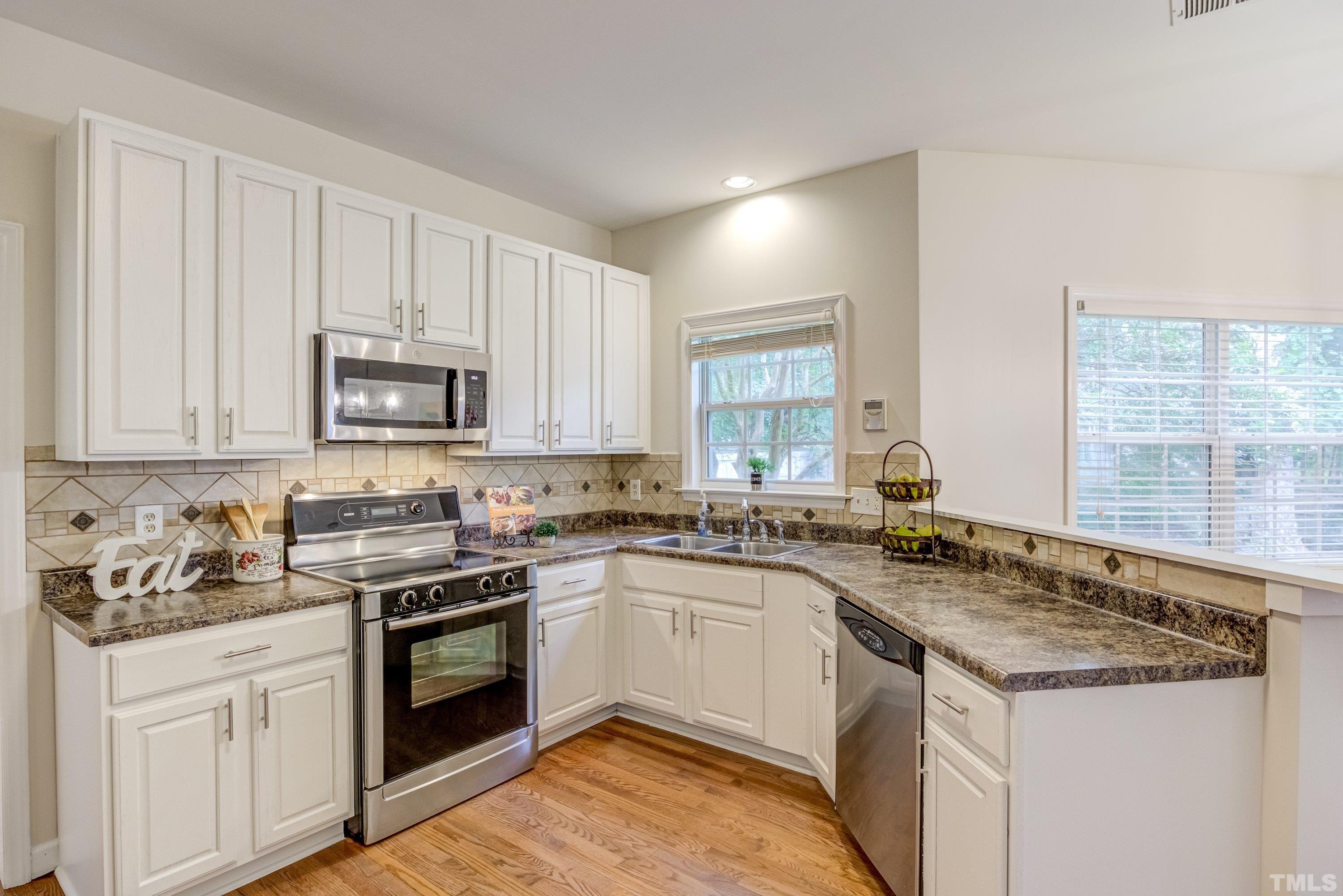 467 Seastone Street Raleigh, NC 27603 - Photo 16 of 38 a kitchen with granite countertop a sink stove and cabinets