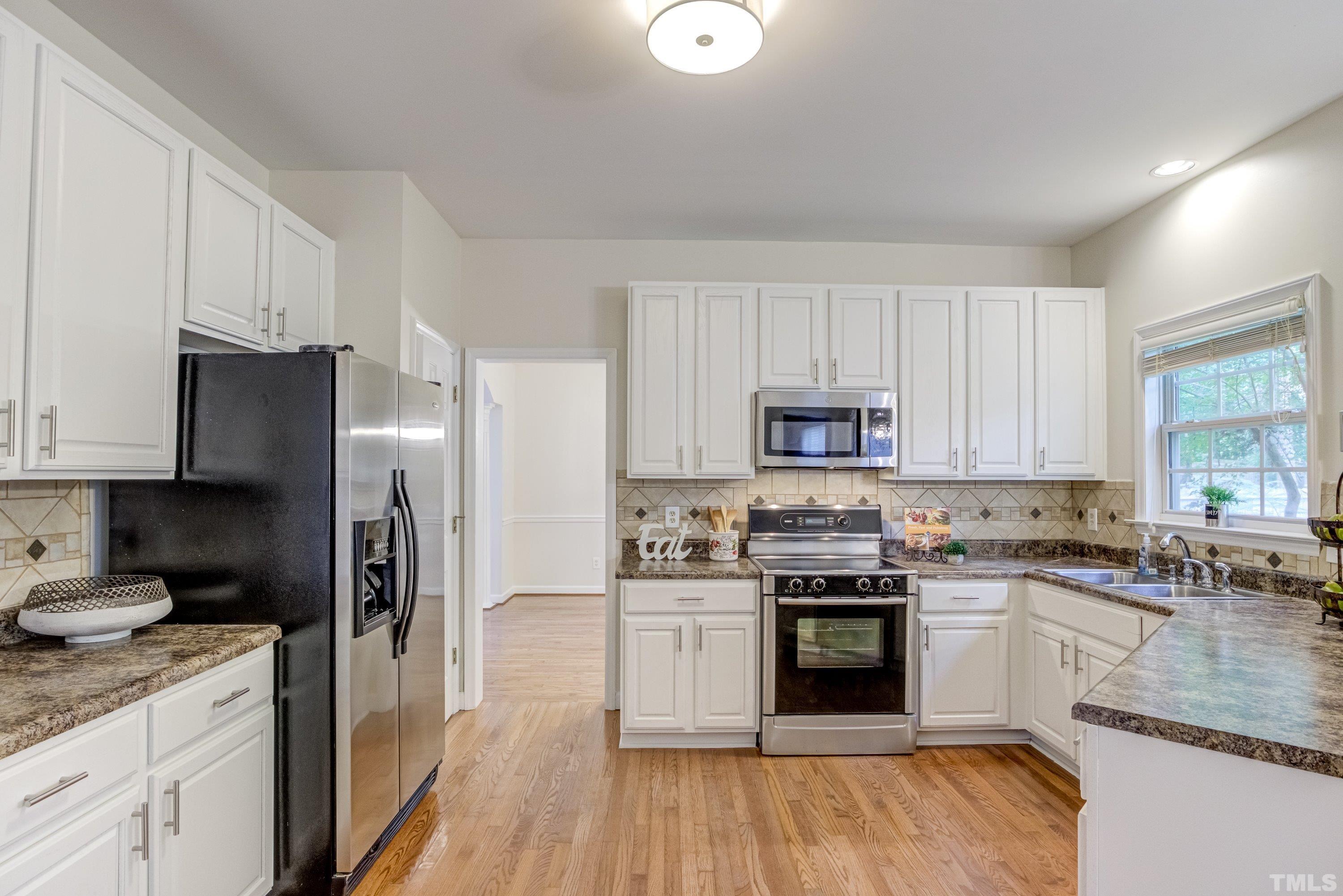 467 Seastone Street Raleigh, NC 27603 - Photo 4 of 38 a kitchen with granite countertop white cabinets and stainless steel appliances