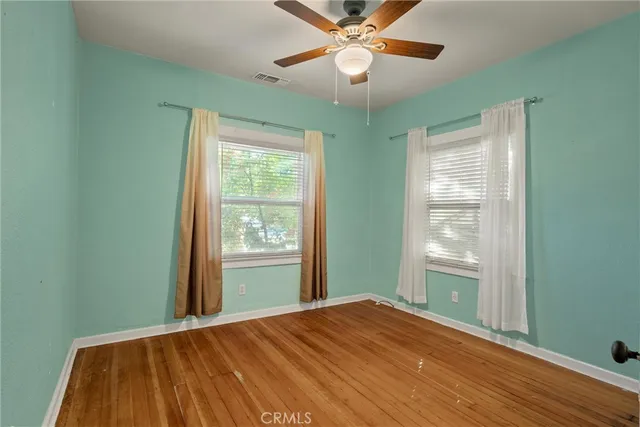 a view of empty room with wooden floor and fan