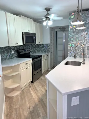 a kitchen with granite countertop a sink stainless steel appliances and white cabinets
