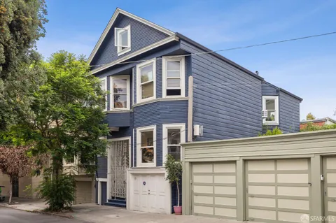 a front view of a house with a tree