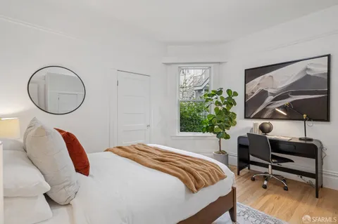 a bedroom with a bed a mirror and a large window