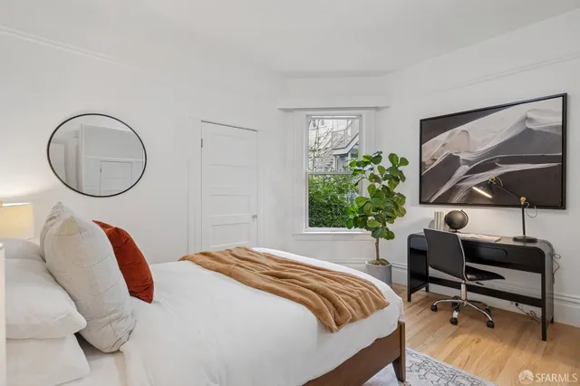 a bedroom with a bed a mirror and a large window