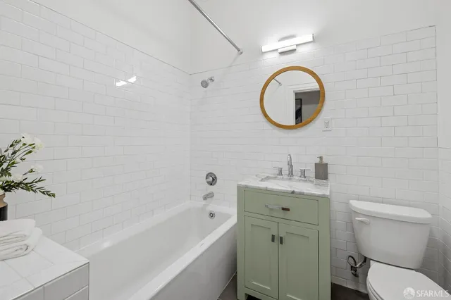 a bathroom with a toilet sink vanity tub and mirror