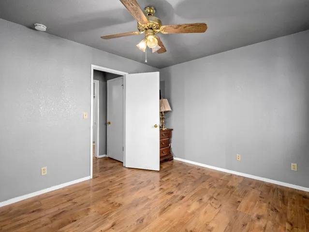 wooden floor in an empty room with a chandelier fan
