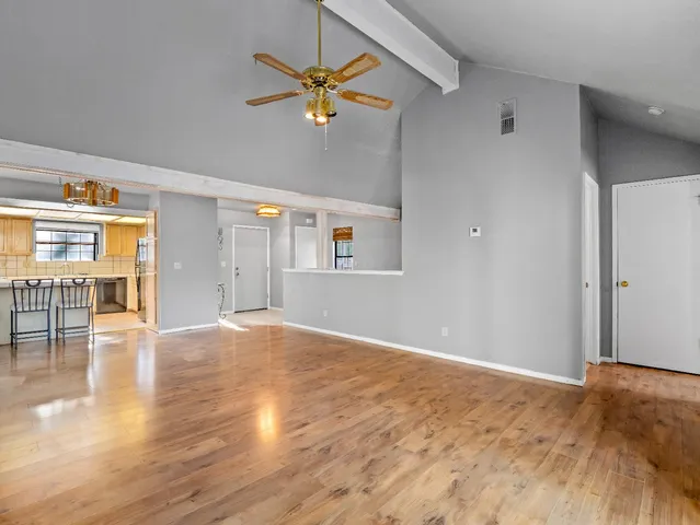 a view of an empty room with window and wooden floor