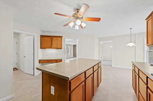 a view of kitchen island a sink wooden floor and a refrigerator