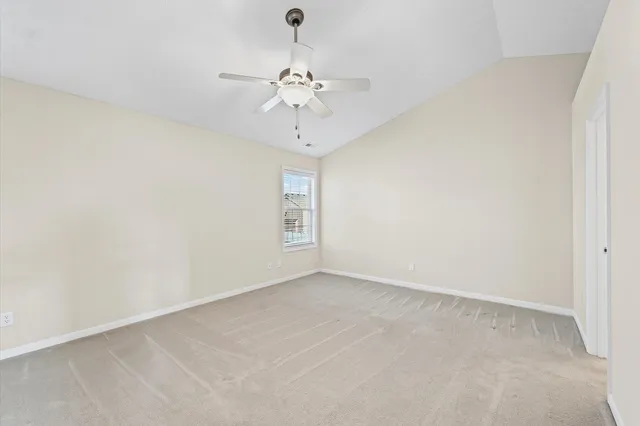 an empty room with a chandelier fan and windows