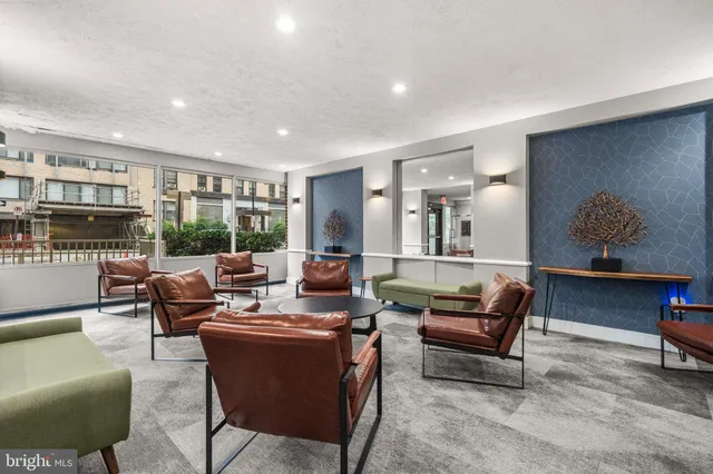 a living room with furniture floor to ceiling window and kitchen view