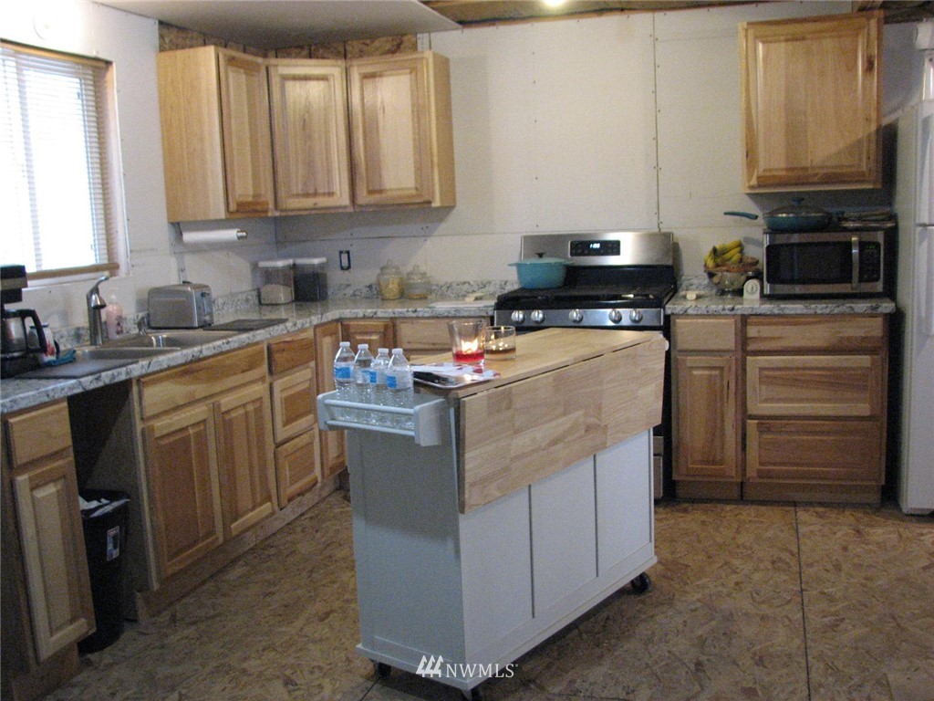 7 Old Ranch Republic, WA 99166 - Photo 22 of 40 a kitchen with kitchen island granite countertop a stove top oven a sink a counter space and cabinets