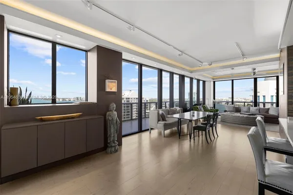 a living room with furniture two large windows and wooden floor