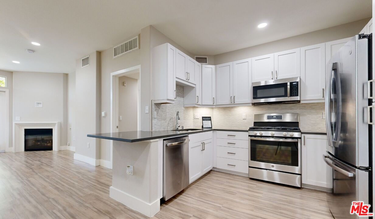 a kitchen with stainless steel appliances granite countertop a stove top oven a sink and a refrigerator