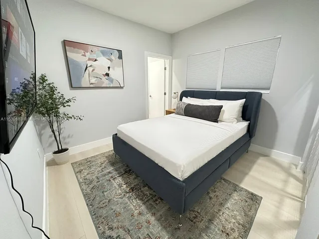 a white bed sitting in a bedroom next to a potted plant