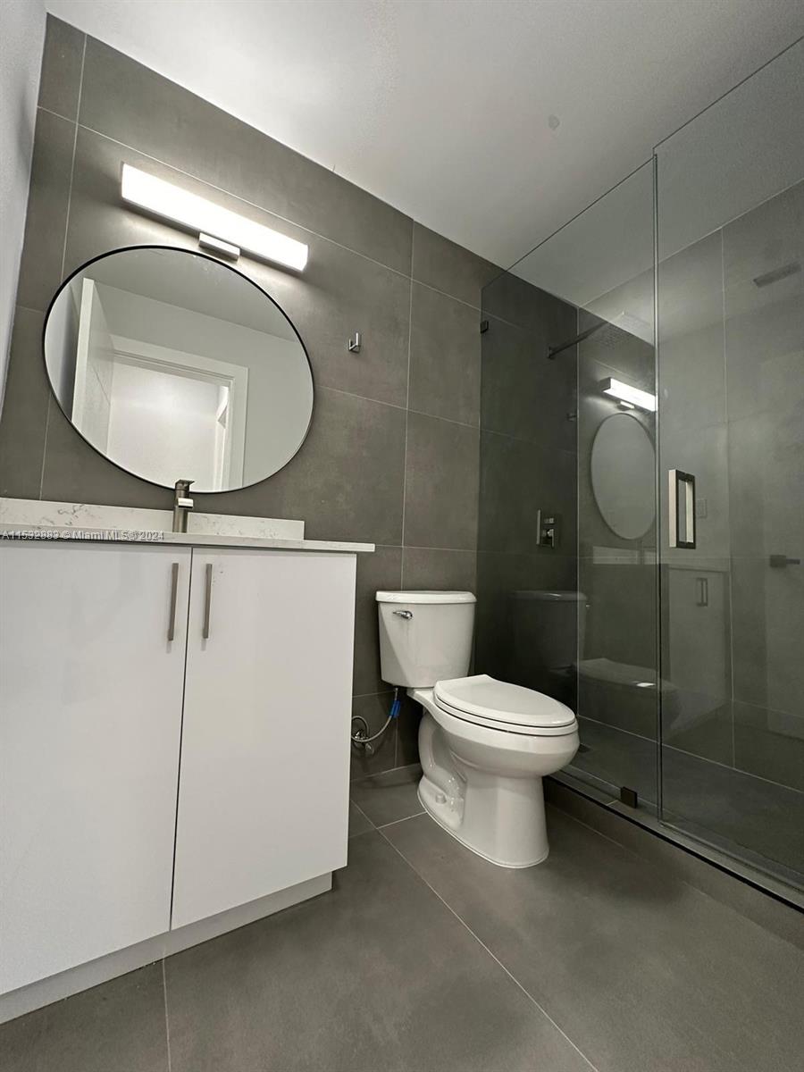 994 Northwest 2nd Street Miami, FL 33128 - Photo 23 of 30 a bathroom with a toilet a sink and mirror