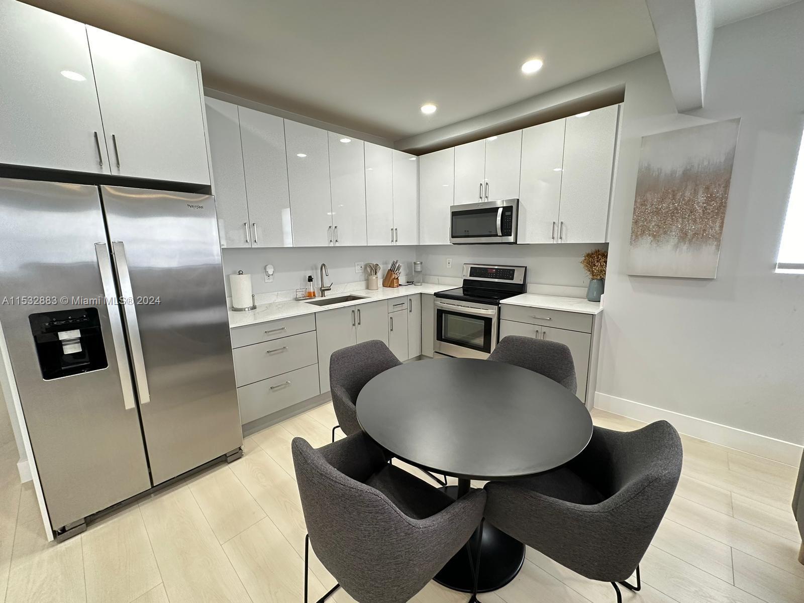 994 Northwest 2nd Street Miami, FL 33128 - Photo 5 of 30 a kitchen with stainless steel appliances granite countertop a sink a microwave a refrigerator and a stove