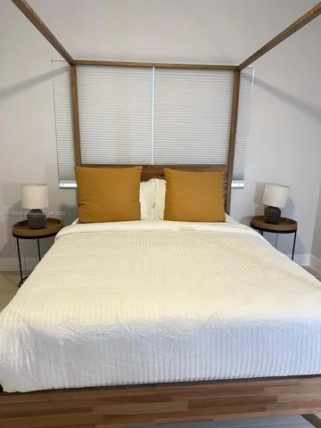 a large bed sitting in a bedroom next to a lamp with a wooden floor