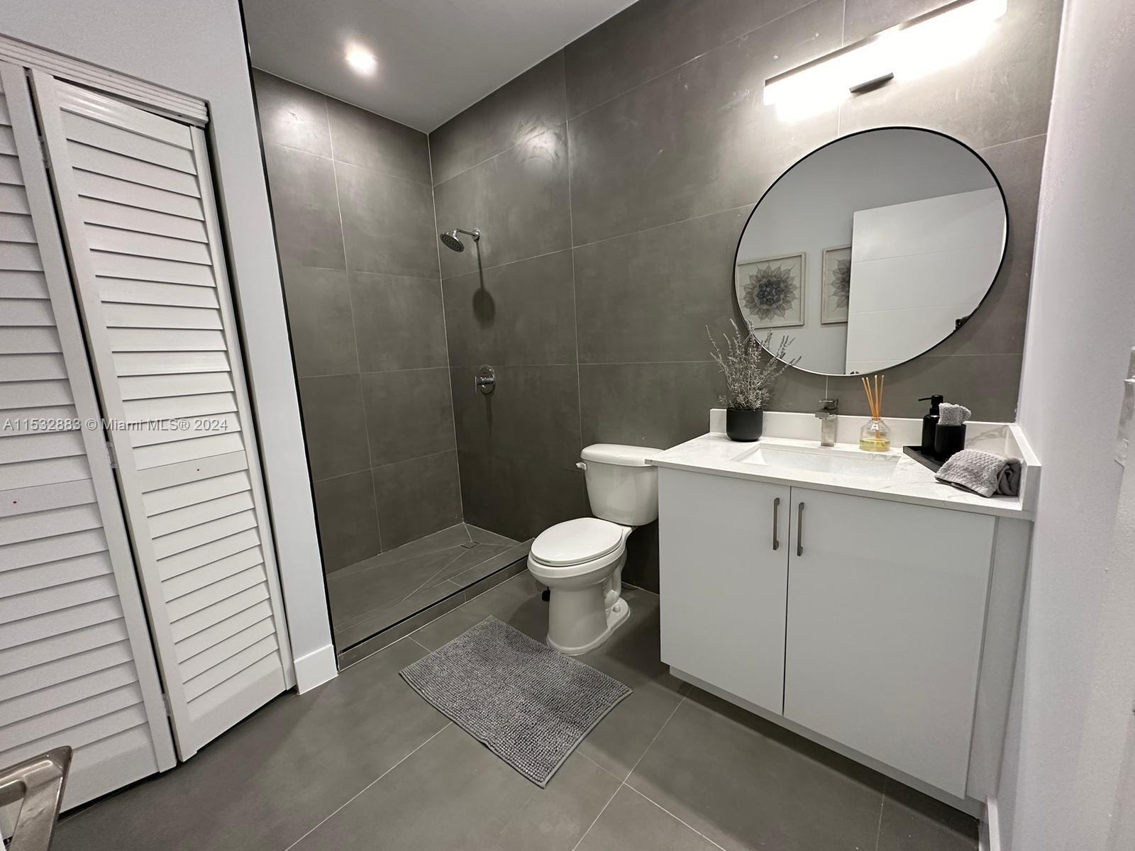 994 Northwest 2nd Street Miami, FL 33128 - Photo 10 of 30 a bathroom with a toilet a sink and a mirror