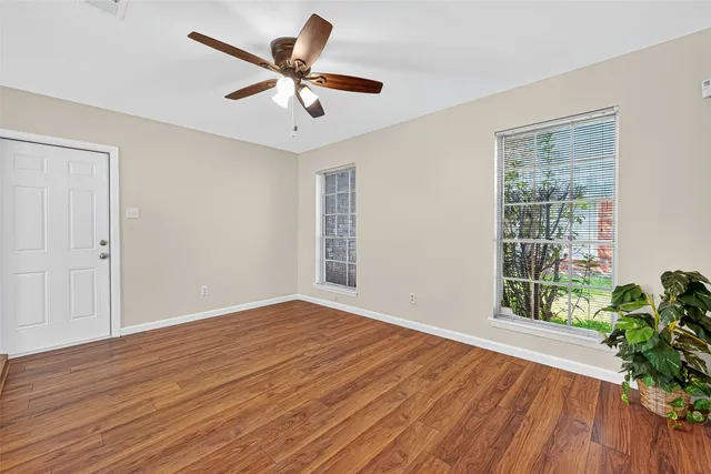 a view of an empty room with wooden floor and a window