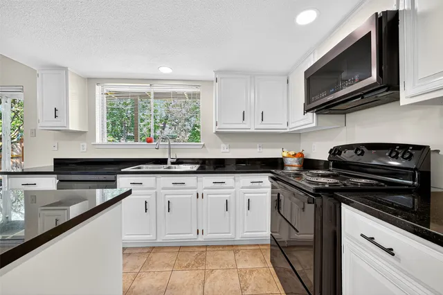 a kitchen with stainless steel appliances granite countertop white cabinets granite counter tops and a window