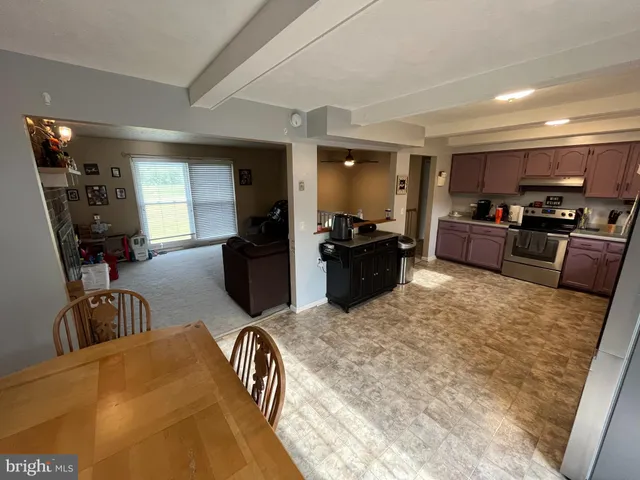 a living room with furniture a flat screen tv and a refrigerator