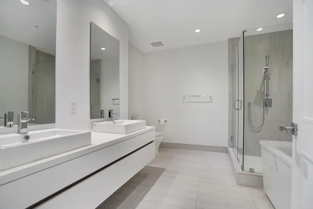 a spacious bathroom with a double vanity sink mirror and shower