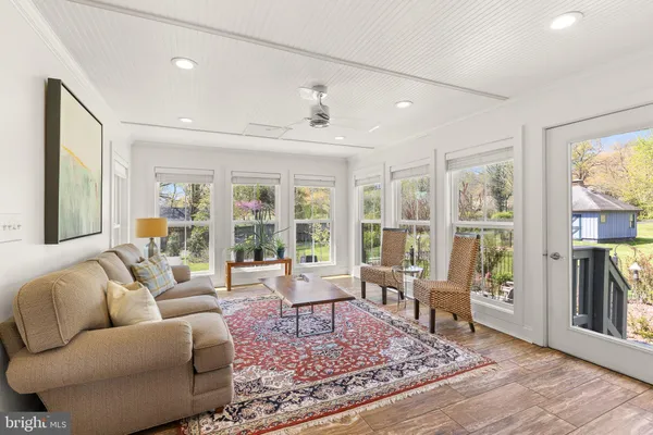 a living room with furniture large windows and wooden floor