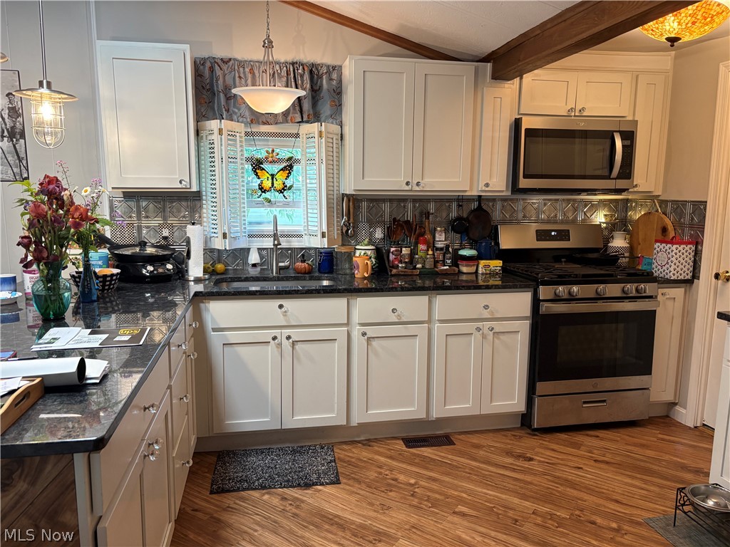 8701 Mayfield Road, Unit 148 Chesterland, OH 44026 - Photo 3 of 24 Kitchen featuring wood-finish flooring, white cabinetry, dark countertops, and stainless steel appliances